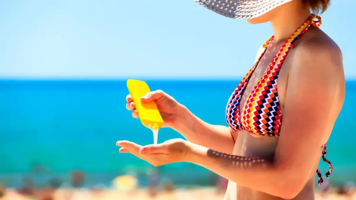 Frau trägt Sonnencreme auf, um sich vor der Sonne zu schützen. Wichtig: Sonnencreme mehrmals auftragen!