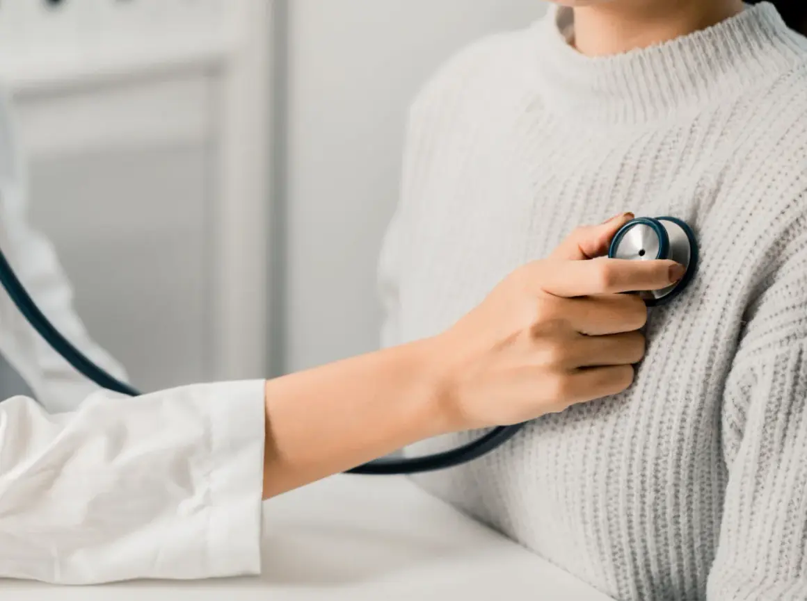 Un médecin écoute le cœur d'une patiente, cherchant un petit souffle au cœur.