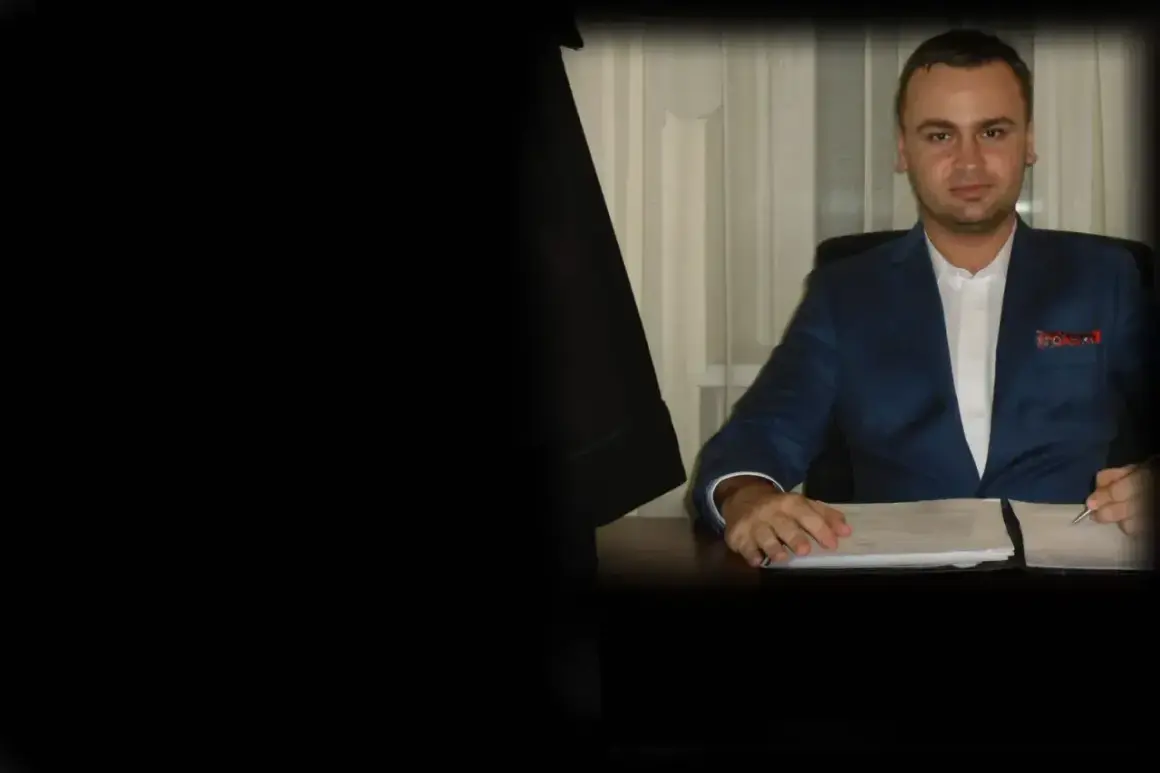 Mężczyzna w garniturze siedzi przy biurku z dokumentami.