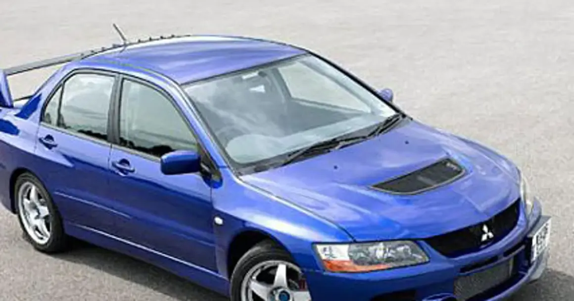 Niebieski Mitsubishi Lancer Evo 9 z charakterystycznym wlotem powietrza na masce i dużym spojlerem, gotowy do akcji.