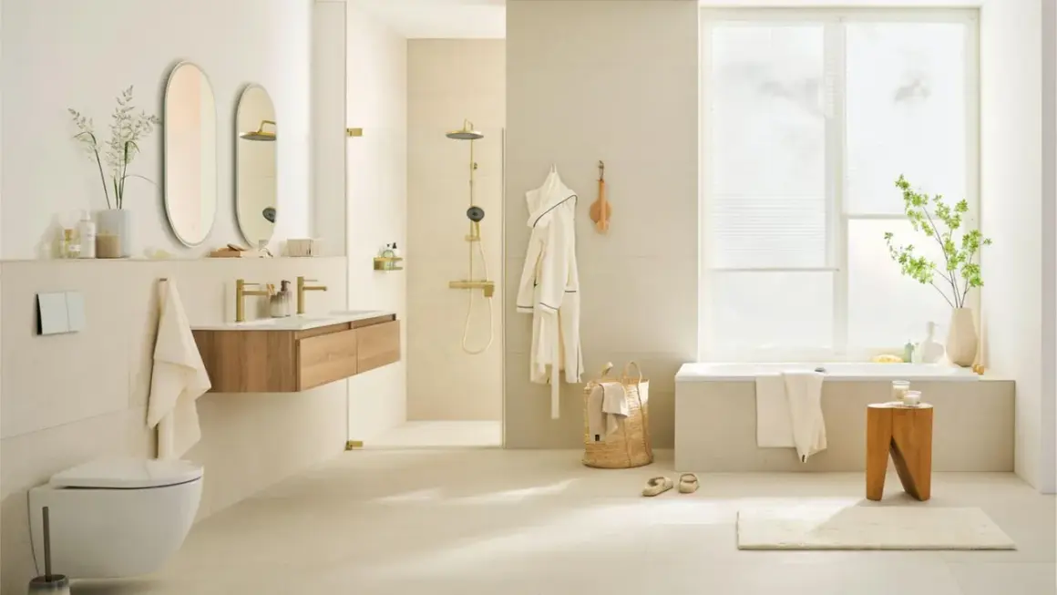 Helles, modernes Badezimmer mit cremefarbener Wandgestaltung. Goldene Armaturen und Duschkopf setzen Akzente. Die Farbgestaltung des kleinen Badezimmers ist beruhigend.
