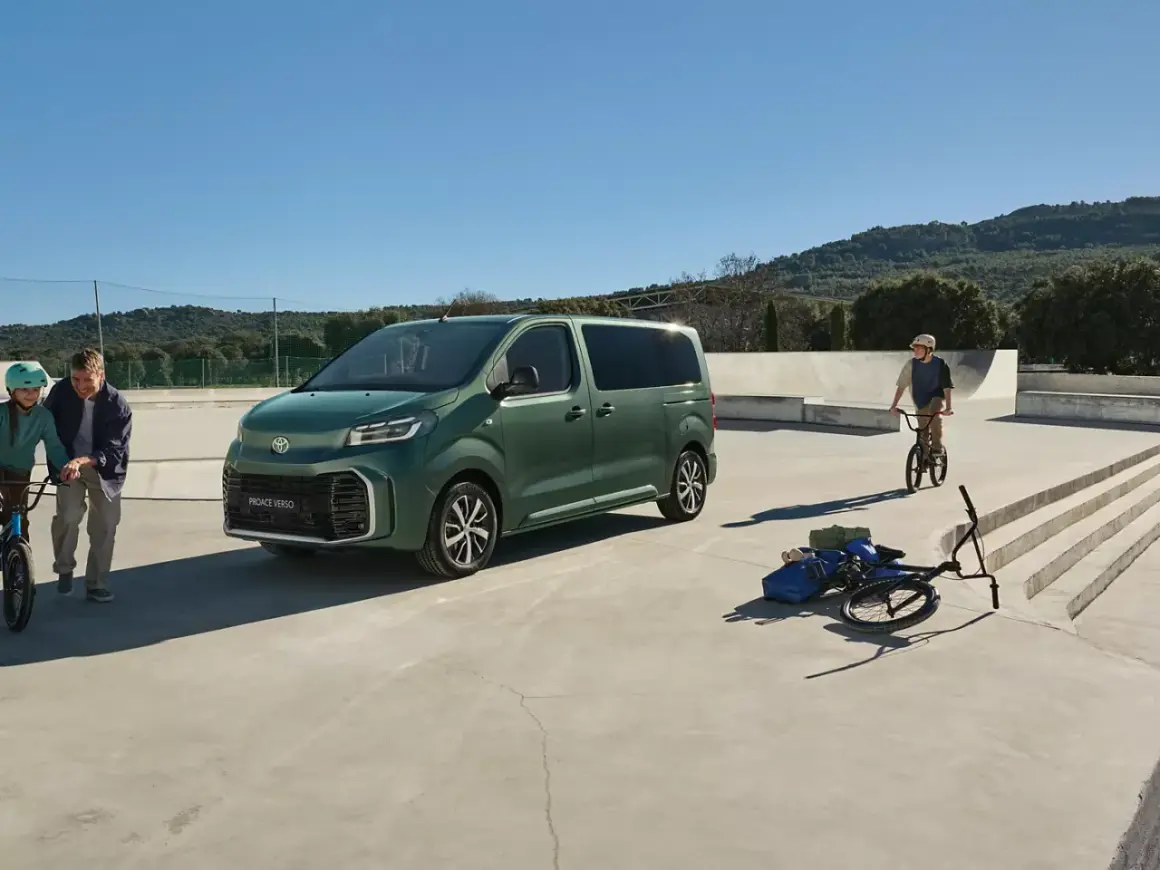 Grön Toyota Proace Verso parkerad vid en skatepark. En pappa och dotter med cyklar, en pojke på BMX.