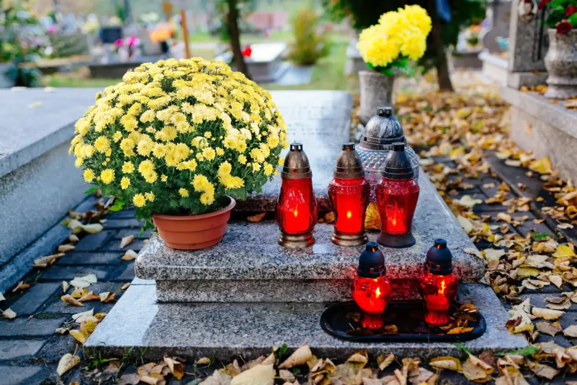 Na grobie bujne żółte chryzantemy, symbolizujące pamięć i szacunek. Płonące znicze dodają powagi.