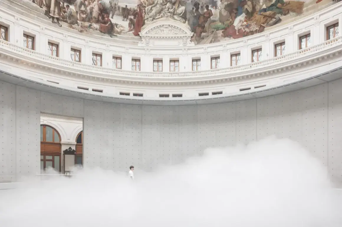 Un homme seul dans un nuage de vapeur au centre de la rotonde de la **Fondation Pinault Paris**, sous une fresque monumentale.