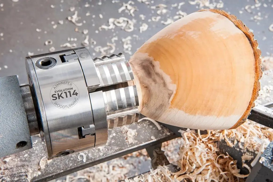 Mandrin de tour à bois fait maison, prêt à façonner un objet en bois. Copeaux de bois éparpillés.