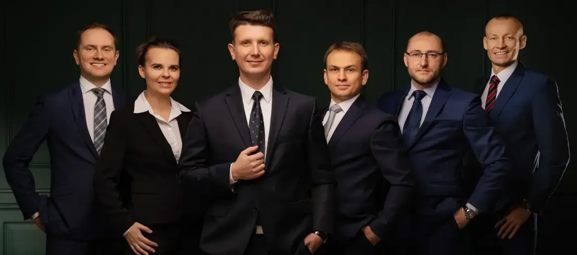 Grupa sześciu profesjonalistów w garniturach, stojących obok siebie.