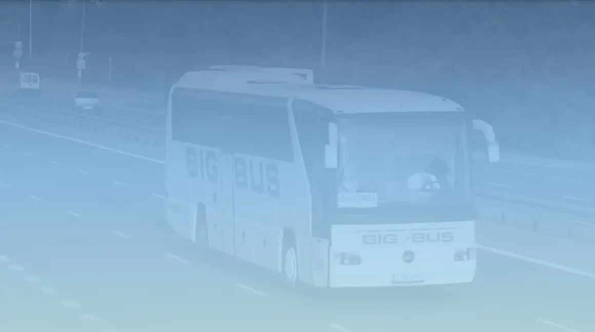 Autobus "BIG BUS" z napisem "WARSZAWA" jedzie autostradą. Może to być busy z Warszawy do Lublina, mijając Pałac Kultury w oddali.