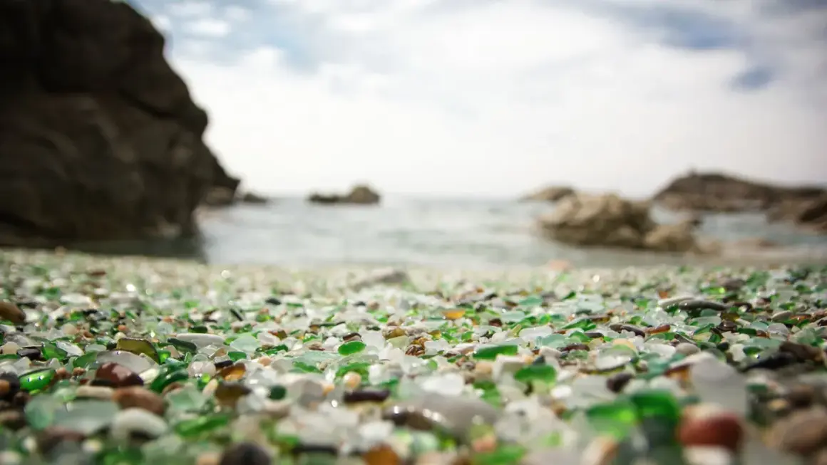 La playa de los cristales, un tesoro de vidrio pulido por el mar, se extiende ante rocas y el océano.