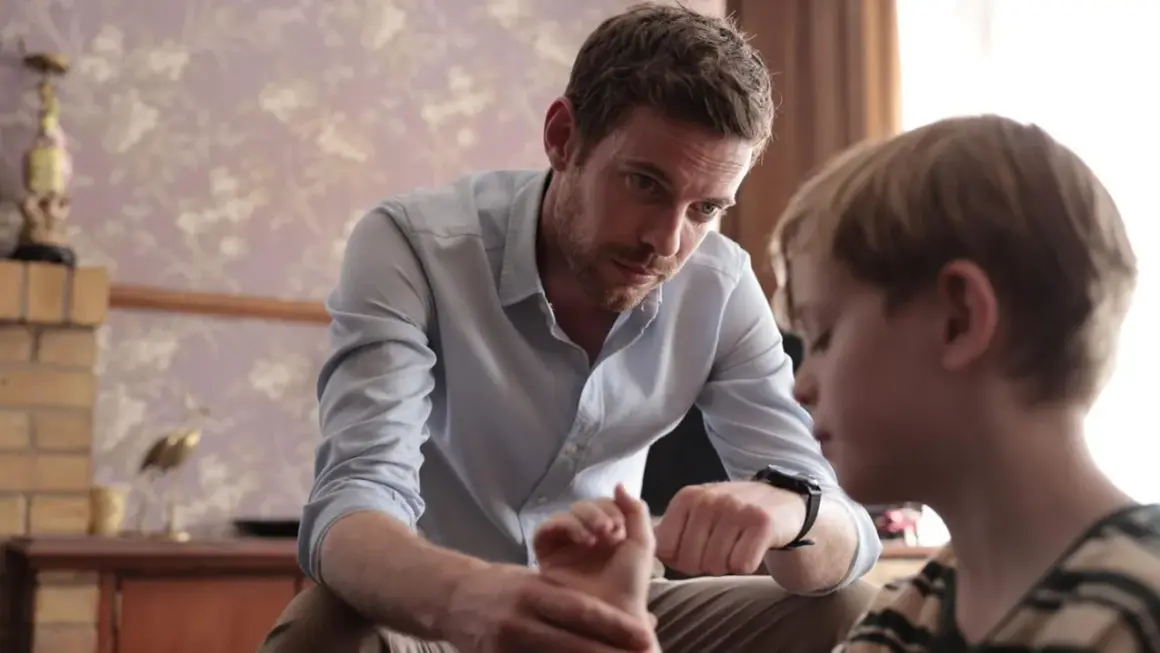 Ein Mann spricht mit einem Jungen, dessen Hand er hält. Die Szene erinnert an die Serie "Chemie des Todes".