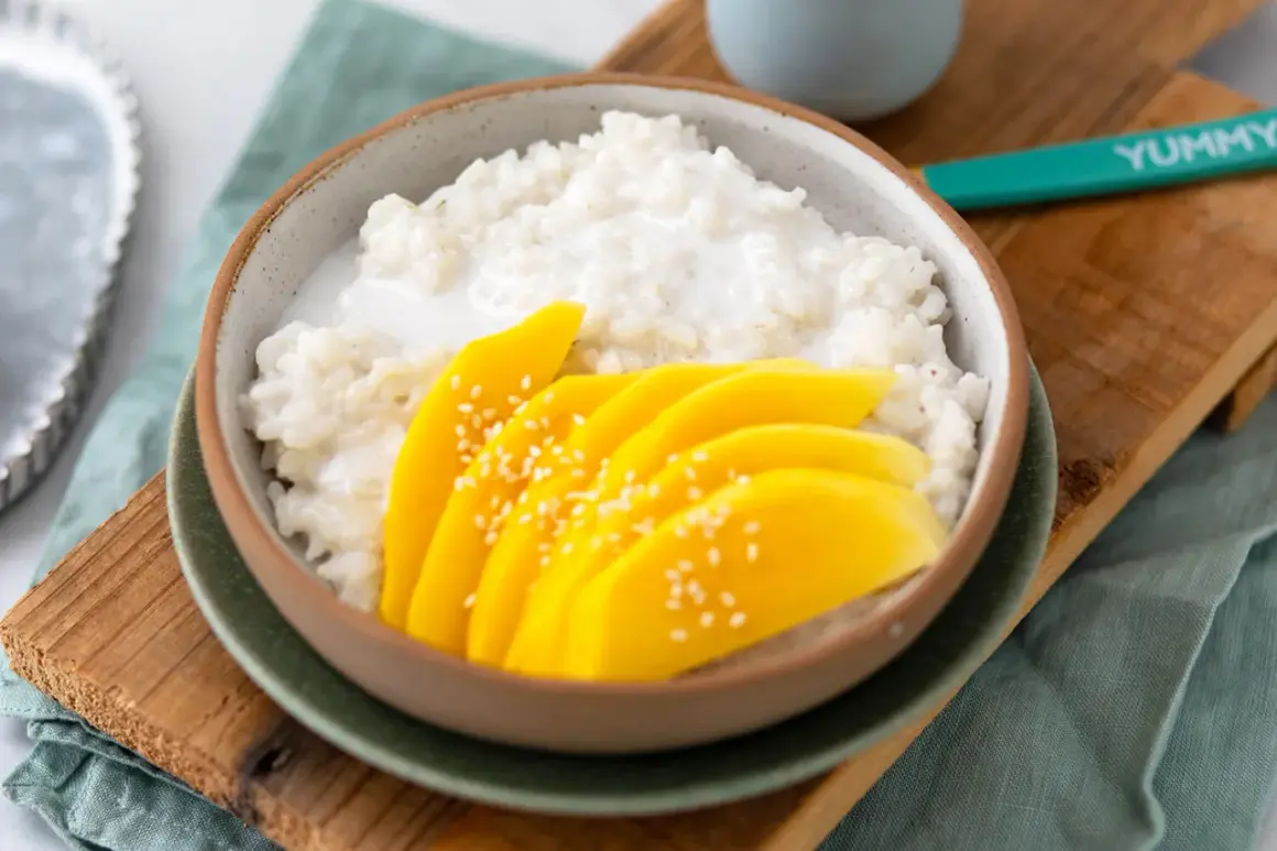 Ein Schälchen mit cremigem Klebreis und frischen Mangoscheiben, bestreut mit Sesam. Perfekt für ein Mango Sticky Rice Rezept.