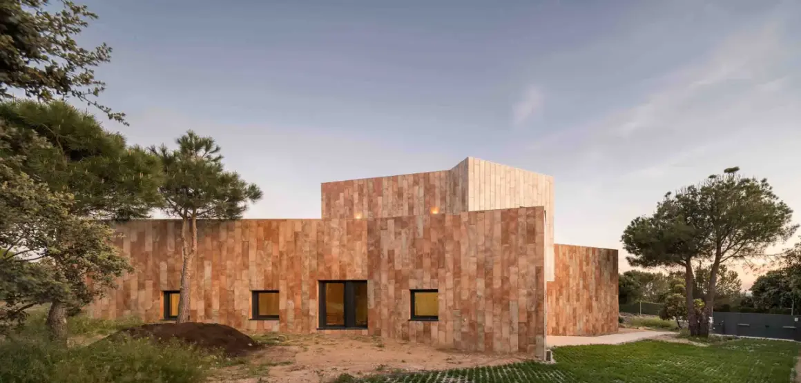 Edificio moderno con paredes porcelanico para fachadas exteriores, rodeado de vegetación y bajo un cielo despejado.