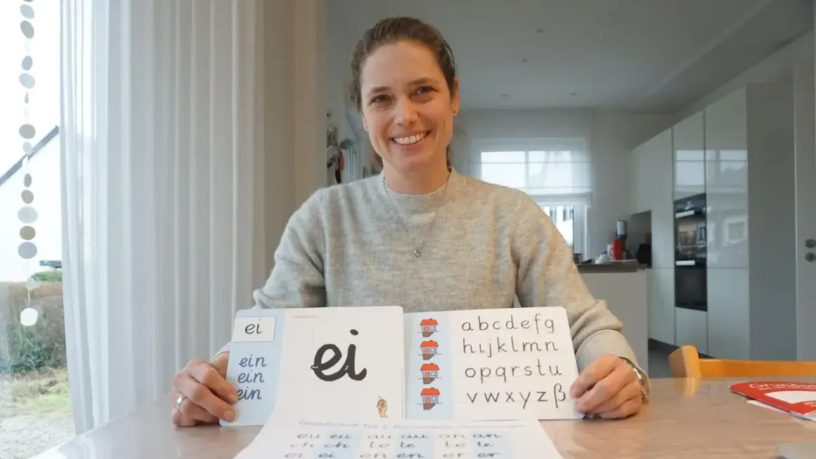 Lehrerin zeigt Grundschulkindern den Buchstaben S und das Alphabet.
