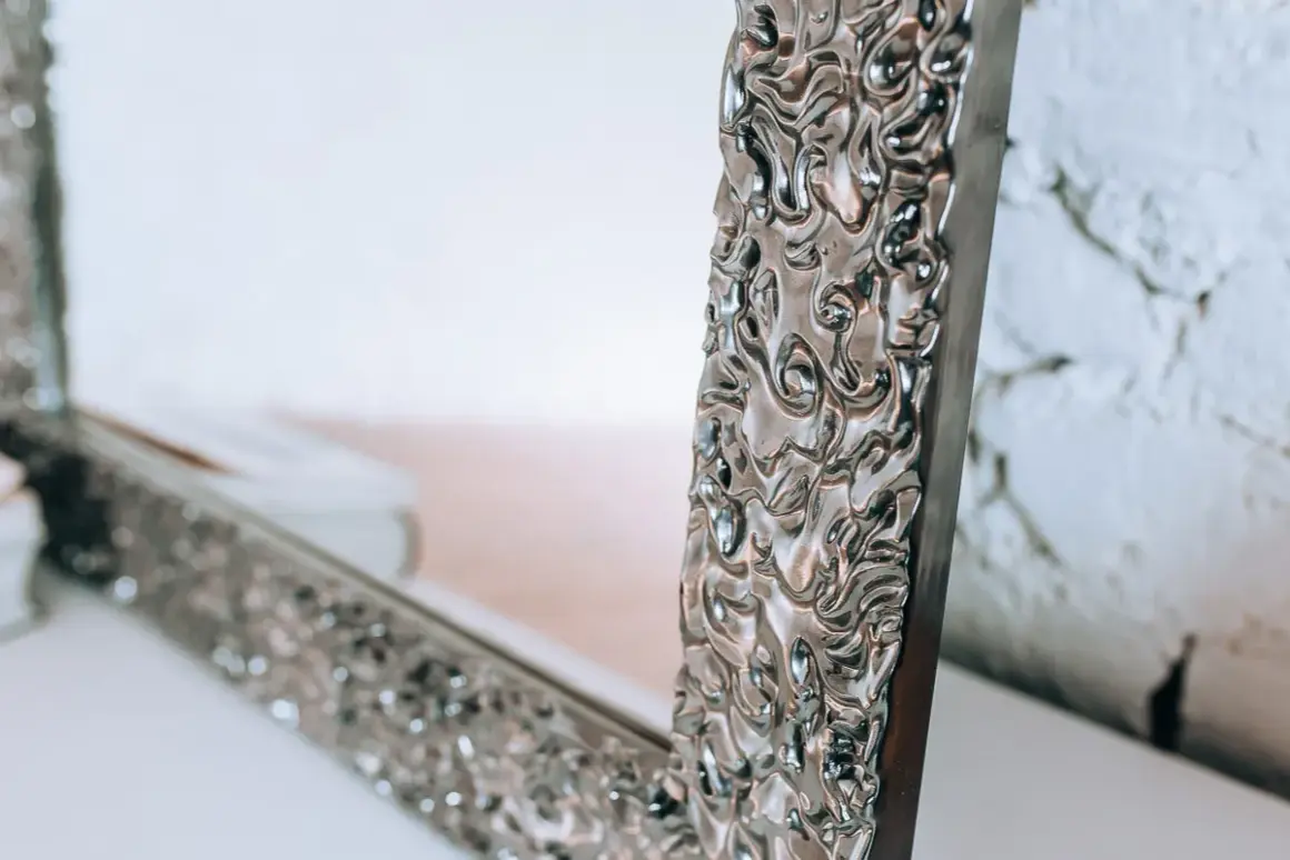 Eleganckie lustro do sypialni glamour z bogato zdobioną, srebrną ramą.