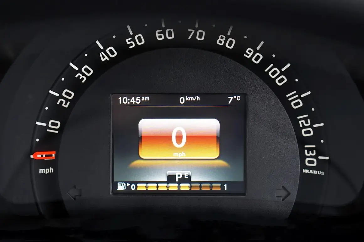 Wyświetlacz cyfrowy na desce rozdzielczej pokazuje 0 mph, 0 km/h, 7°C i godzinę 10:45. To korekta przebiegu po wymianie licznika.