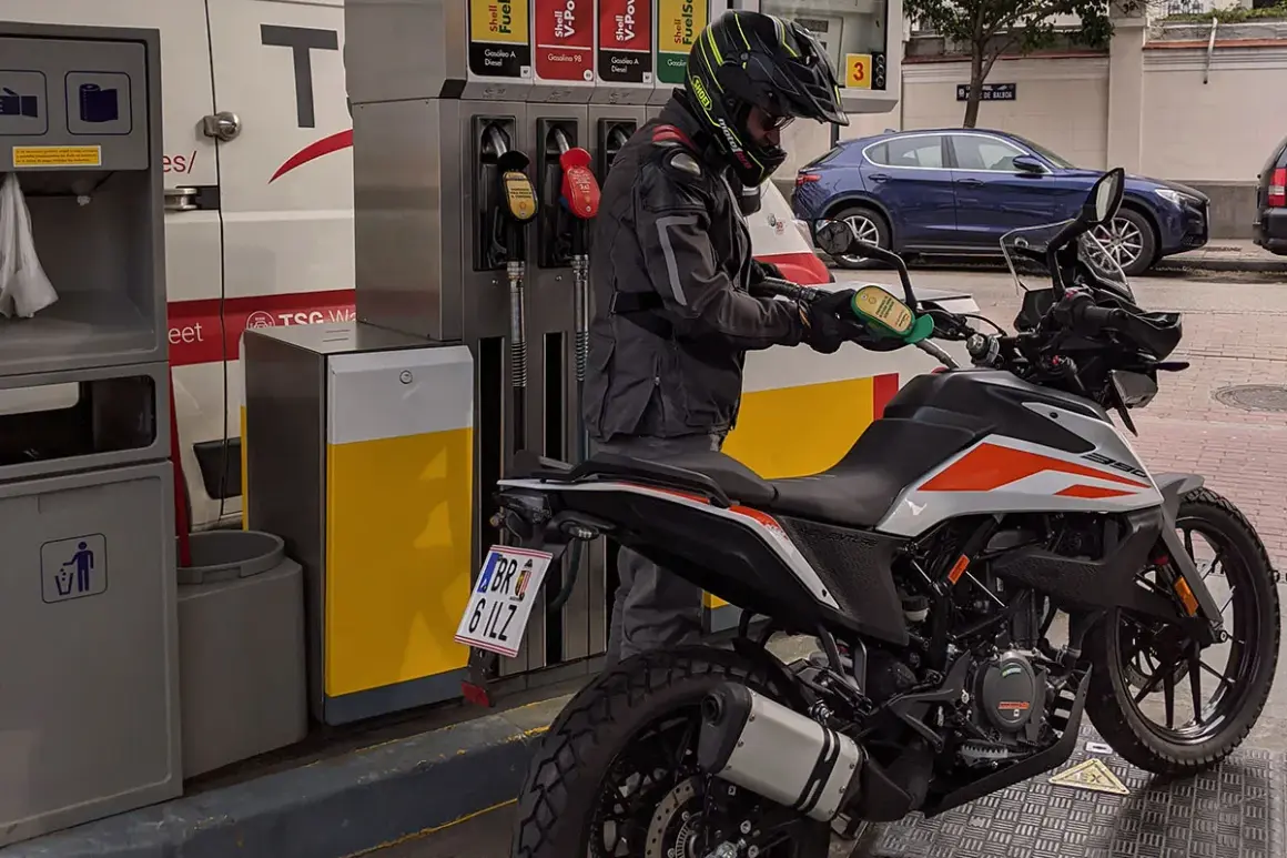 Motociclista repostando su moto 390 Adventure. La pregunta sobre qué gasolina usan las motos de 49cc es relevante para este tipo de vehículos.