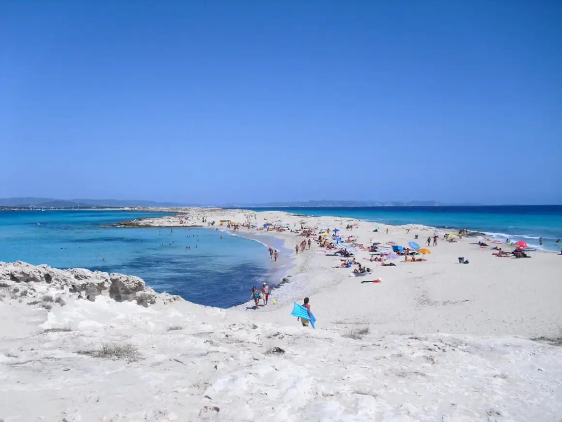 Gente disfrutando de un día soleado en las **playas blancas** con aguas turquesas y cielo azul.