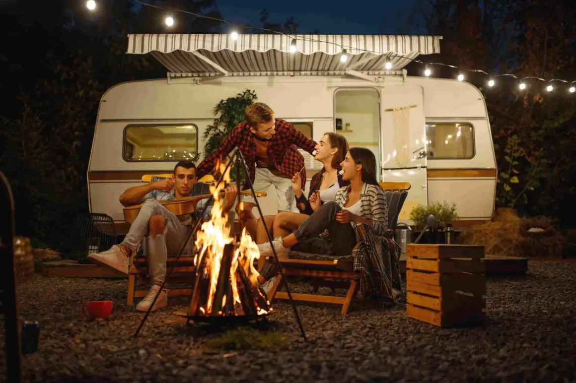 Amigos disfrutan de una fogata y malvaviscos junto a su caravana, una noche perfecta para aprender como acampar.