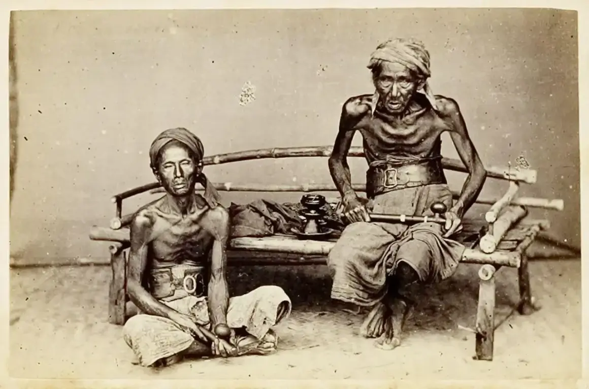 Dos hombres demacrados, víctimas de la guerra del opio, sentados con pipas de opio.