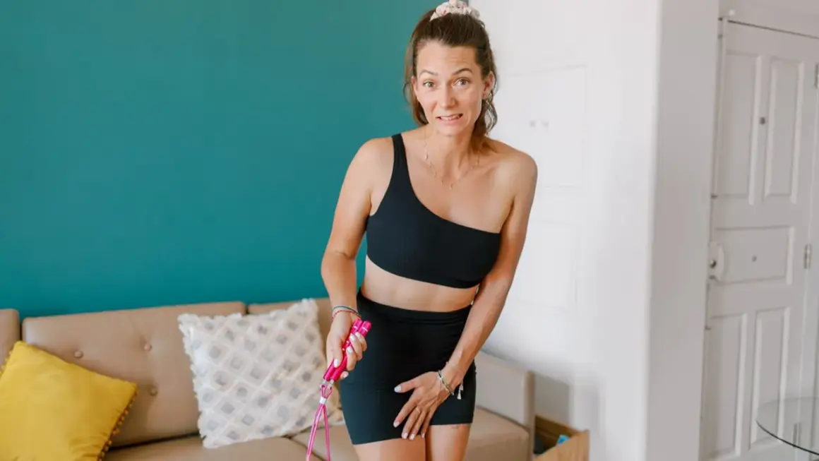 Femme en tenue de sport, inquiète, tenant une corde à sauter. Elle semble se demander "fuites urinaires que faire ?".