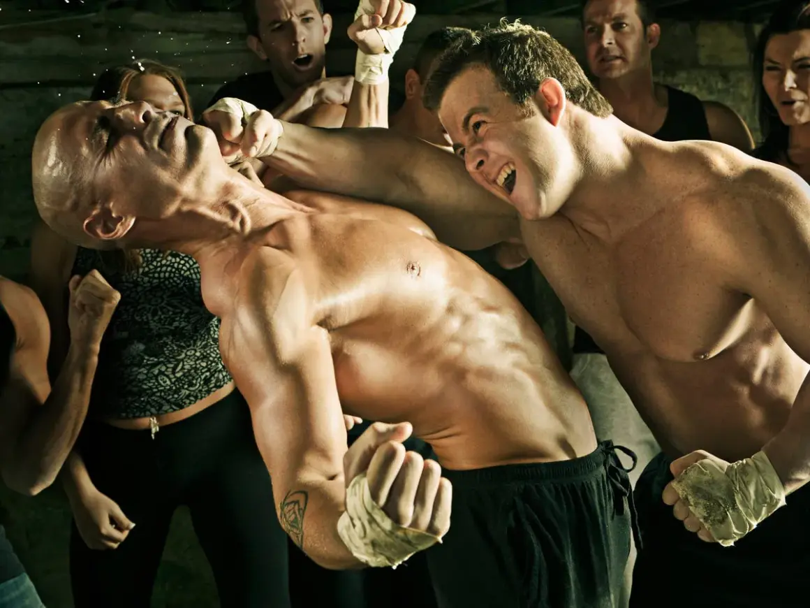 Intense brawlers boxing, one fighter lands a punch as spectators watch.
