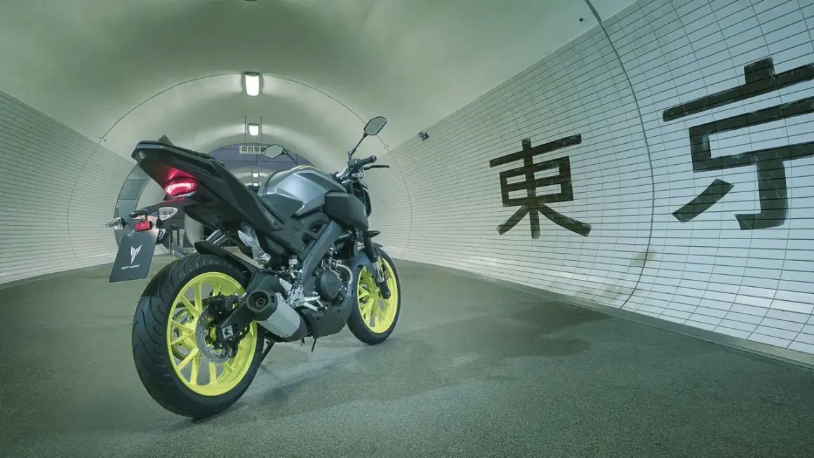 Yamaha MT-125 gris con llantas amarillas en un túnel con caracteres japoneses. ¡Lista para alcanzar su yamaha mt 125 velocidad maxima!
