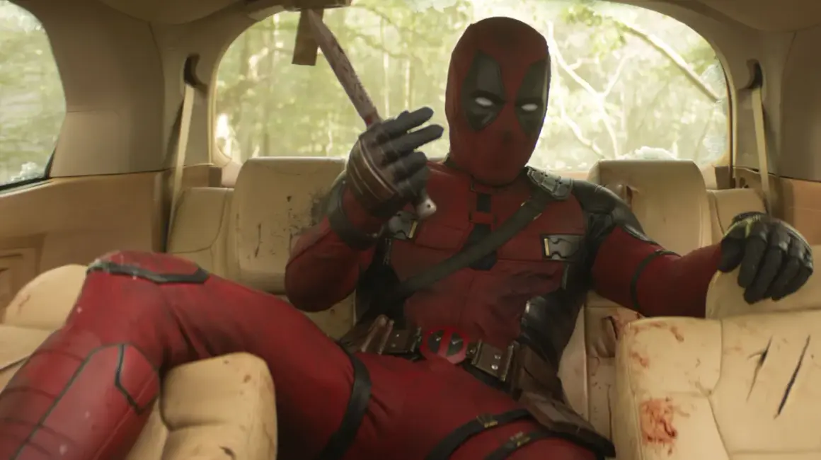 Deadpool, in seinem ikonischen roten Anzug, sitzt lässig im Auto und hält eine blutige Axt. Ein typischer Moment aus den Filmen von Ryan Reynolds.