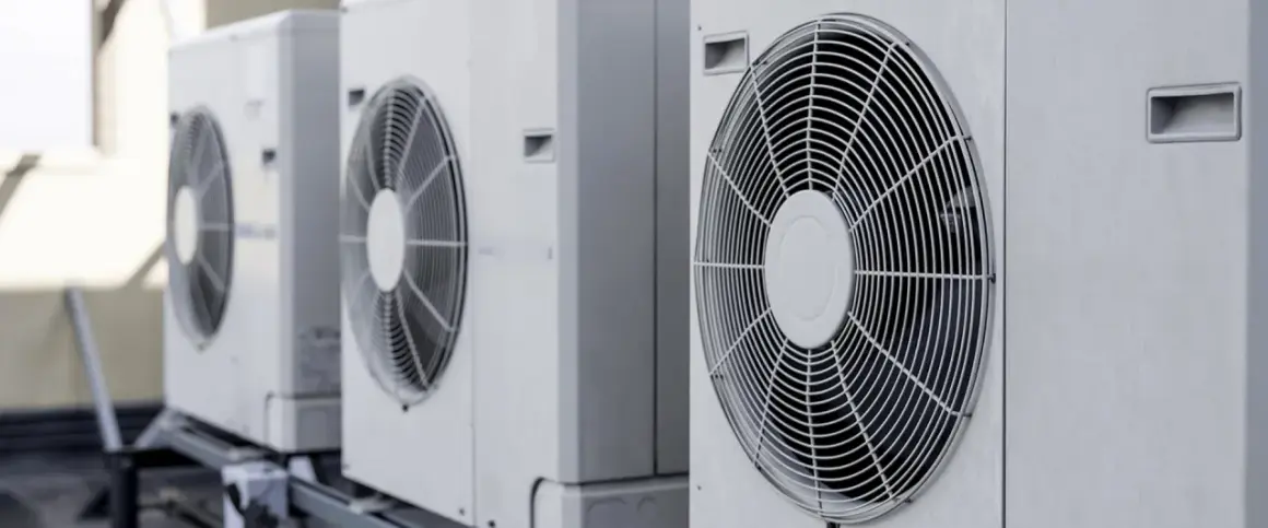 Rząd białych jednostek zewnętrznych, gdzie pompa ciepła i klimatyzacja pracują razem, zapewniając komfort.