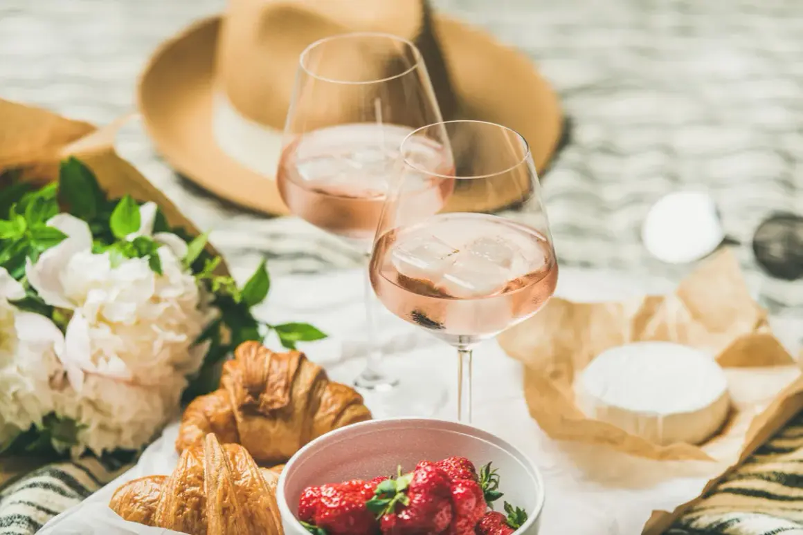 Zwei Gläser mit erfrischenden rose Weine, dazu Croissants, Erdbeeren und Käse. Ein perfektes Picknick!
