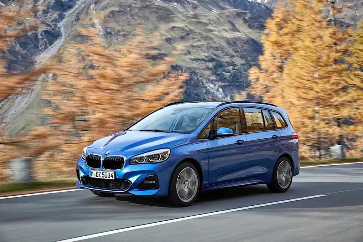 Niebieskie BMW 2 Gran Tourer jedzie po górskiej drodze jesienią.