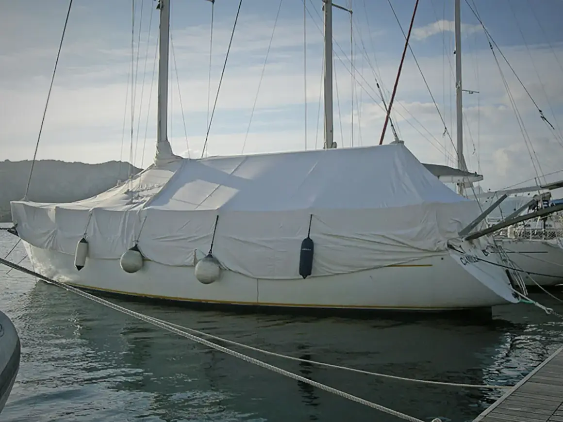 Barca a vela coperta con un telo per barca fai da te, pronta per l'inverno.