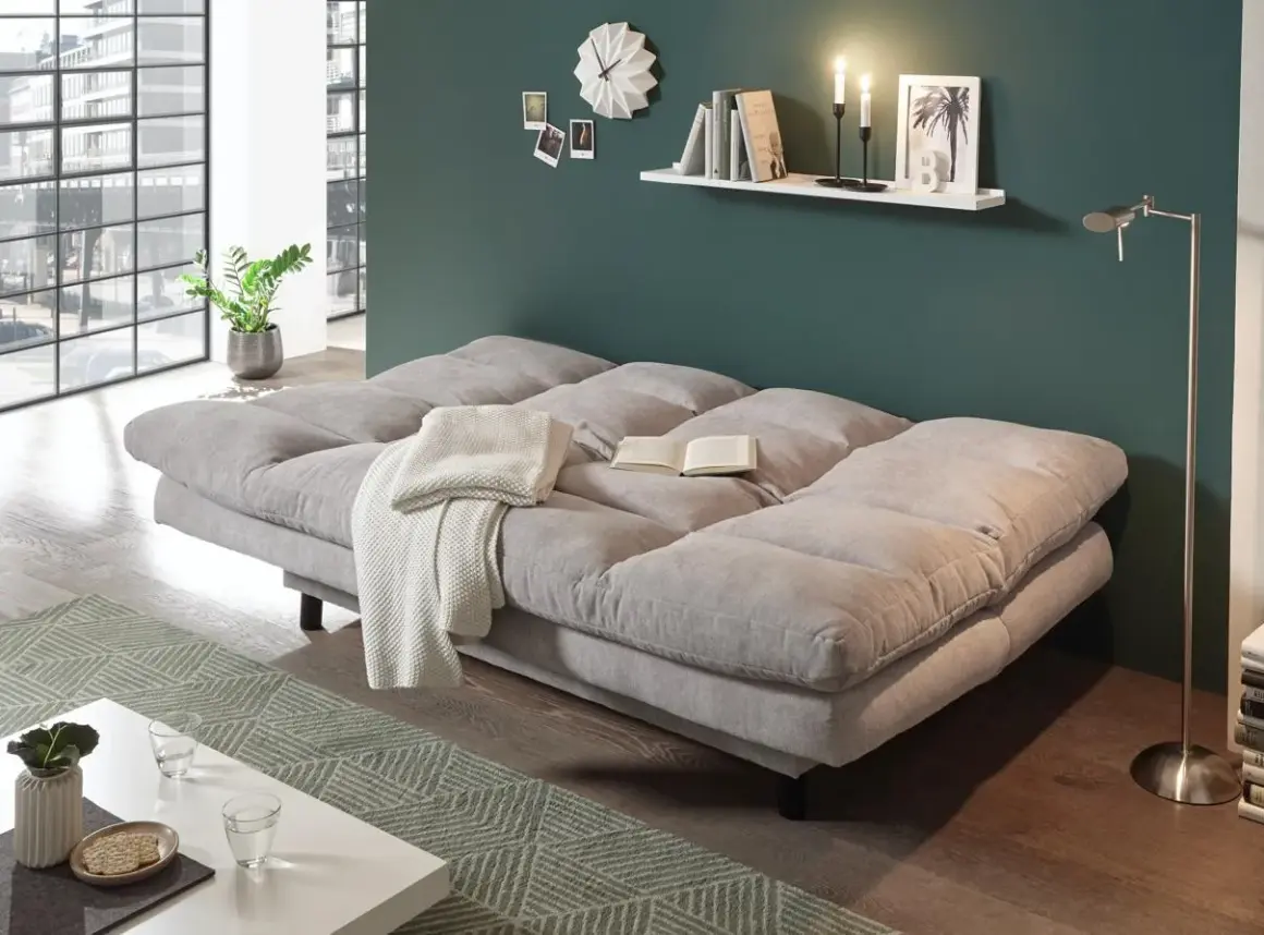 Gemütliches Schlafsofa im Wohnzimmer, ideal zum dauerhaft im wohnzimmer schlafen. Mit Decke und Buch für entspannte Stunden.