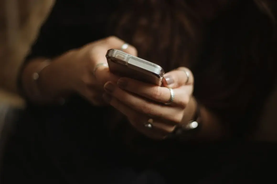 Dłonie z pierścionkami trzymają telefon, być może przeglądając oferty na OLX i myśląc o płatnościach PayPo.