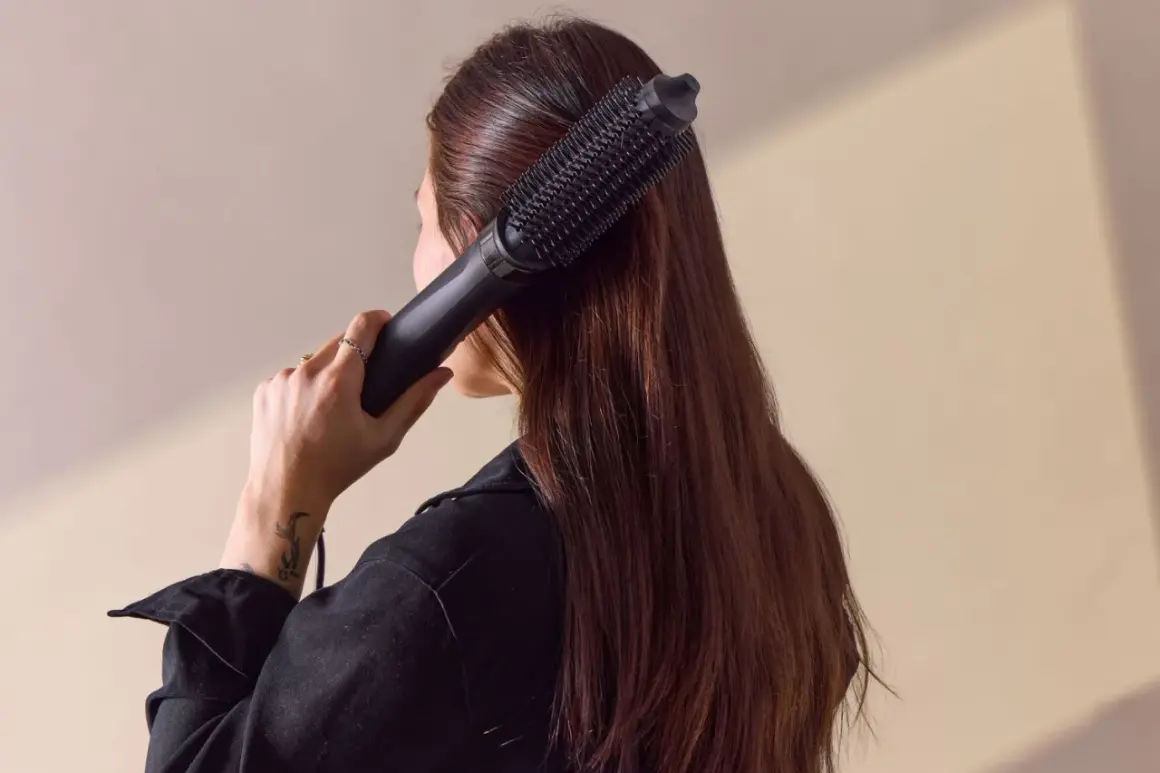 Woman using a black multistyler brush to style her long brown hair.
