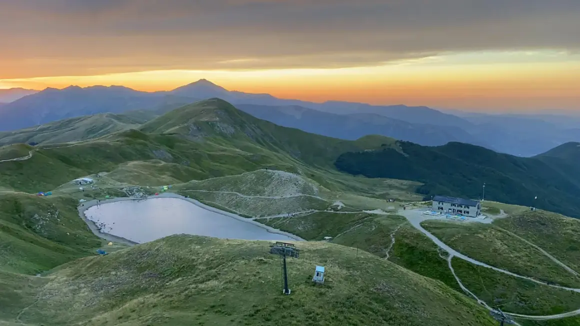 Alba sulle montagne toscane, con un lago alpino e rifugi che ricordano i borghi vicino Abetone.