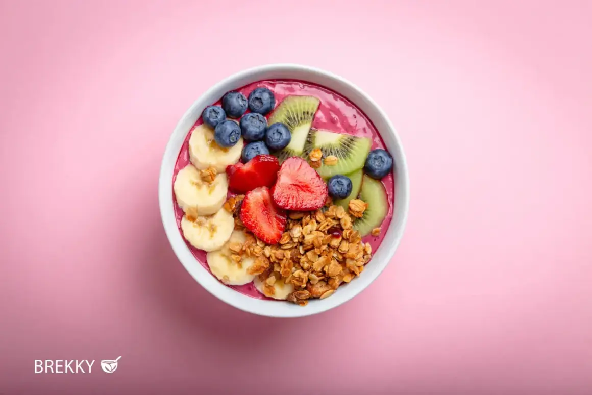 Eine bunte Acai Bowl mit Bananen, Erdbeeren, Blaubeeren und Kiwi, garniert mit Granola.