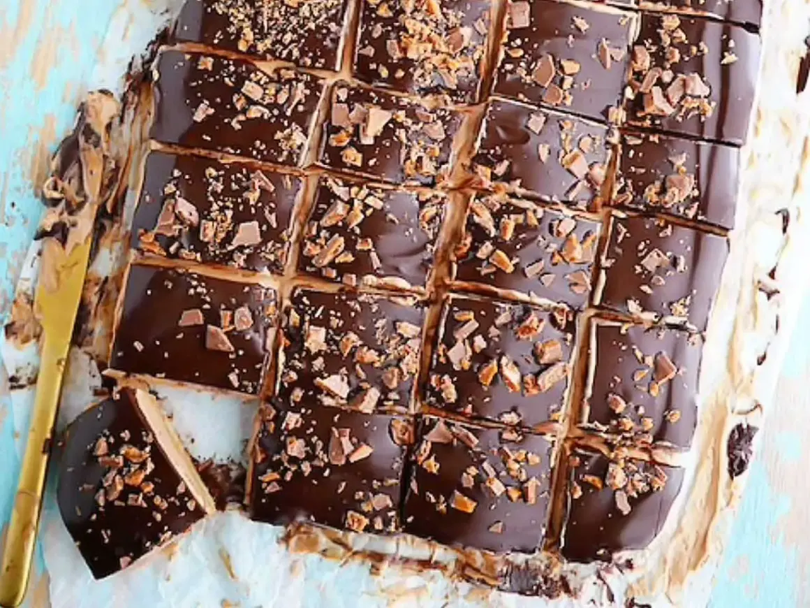 Biskvier i långpanna från Lindas bakskola, täckta med choklad och strössel. En gyllene kniv ligger bredvid.