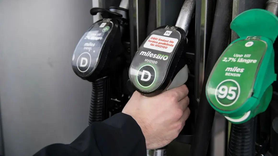 Hand håller dieselslang, funderar på dieseltillsats bra eller dåligt. Bredvid finns bensinslang.