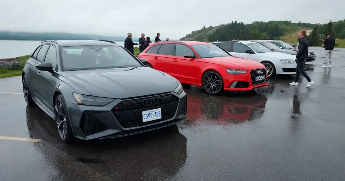 Szare i czerwone Audi RS6 C8 stoją obok siebie na mokrym parkingu.