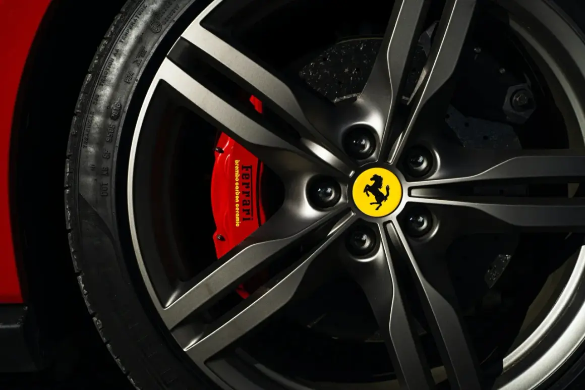 Felga z logo Ferrari, czerwony zacisk hamulcowy Brembo i opona Pirelli. Marka samochodu na i.