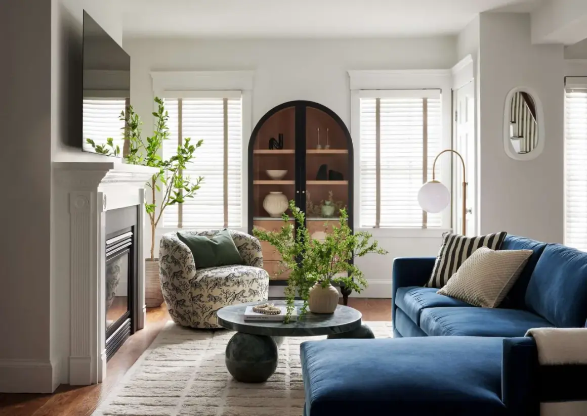 A round coffee table decor features a vase with greenery and a beaded strand, adding a natural touch to the living room.