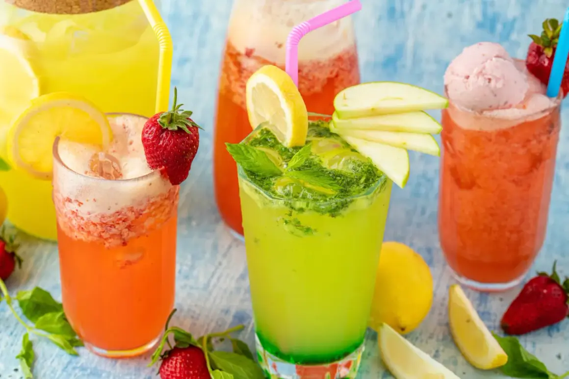 Färgglada alkoholfria drinkar med frukt och is. En grön drink med mynta och äpple, en rosa med jordgubbar och glass, samt en orange.