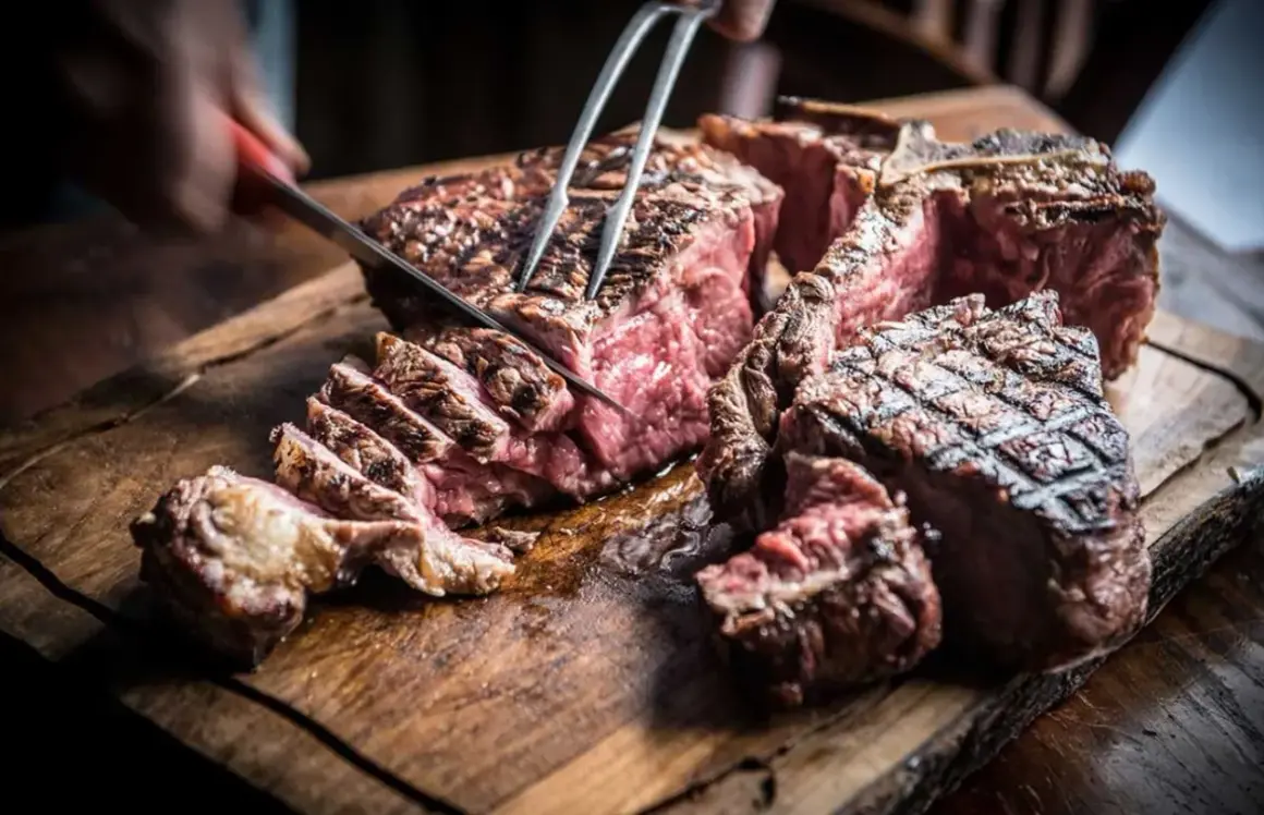 Una succulenta fiorentina steak, tagliata al sangue su un tagliere di legno rustico, con un coltello che affonda nella carne.