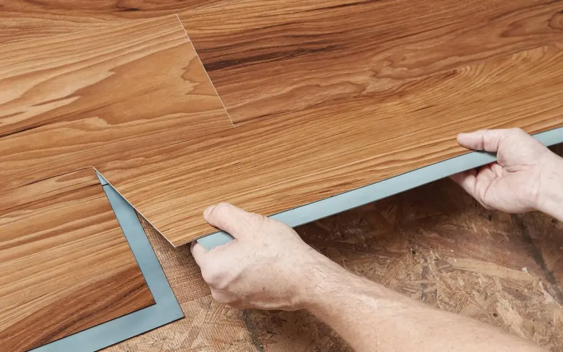 Hands installing wood-look vinyl plank flooring. Once installed, you can walk on vinyl plank flooring immediately.