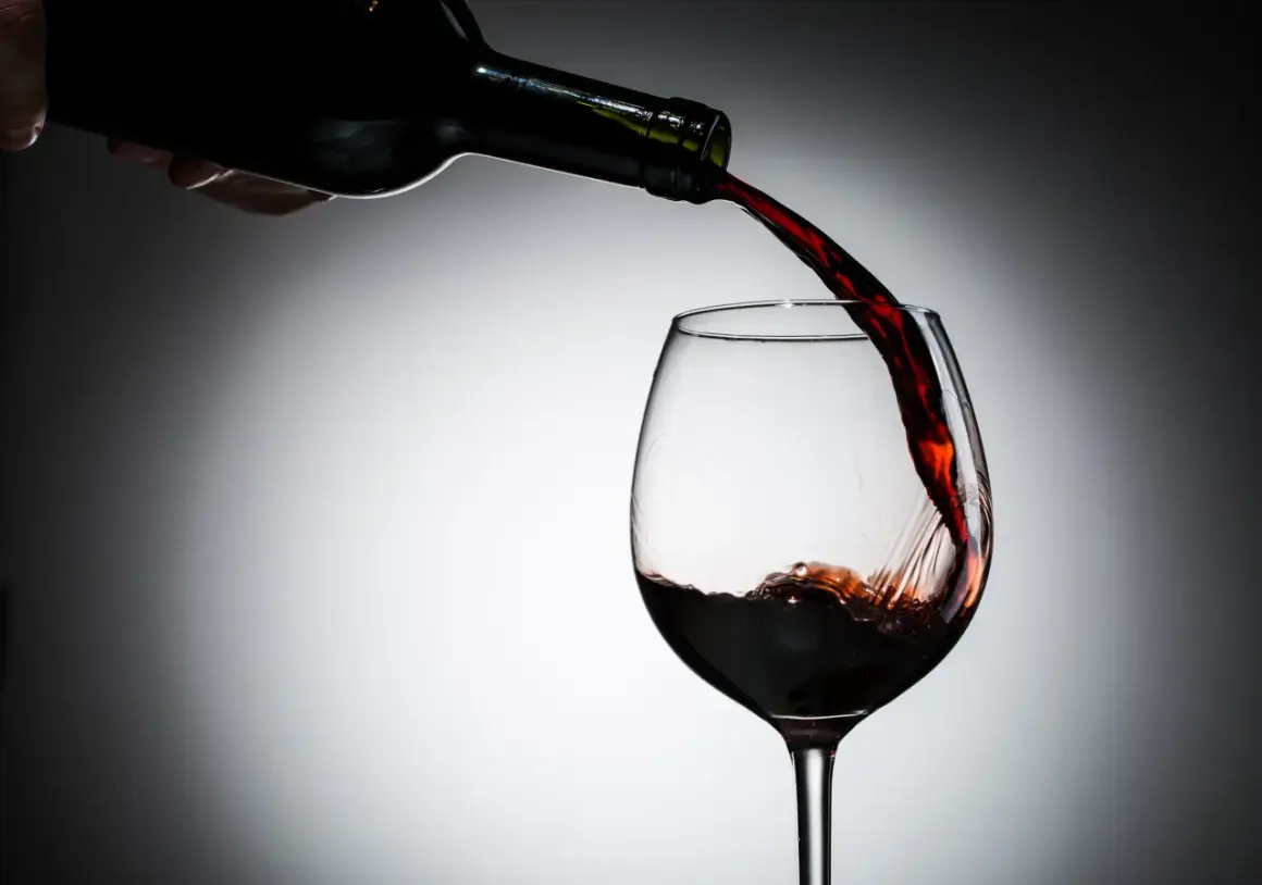 Czerwone wino nalewane do kieliszka. Czy czerwone wino jest zdrowe? Dyskusja trwa, ale jego piękny kolor zachwyca.