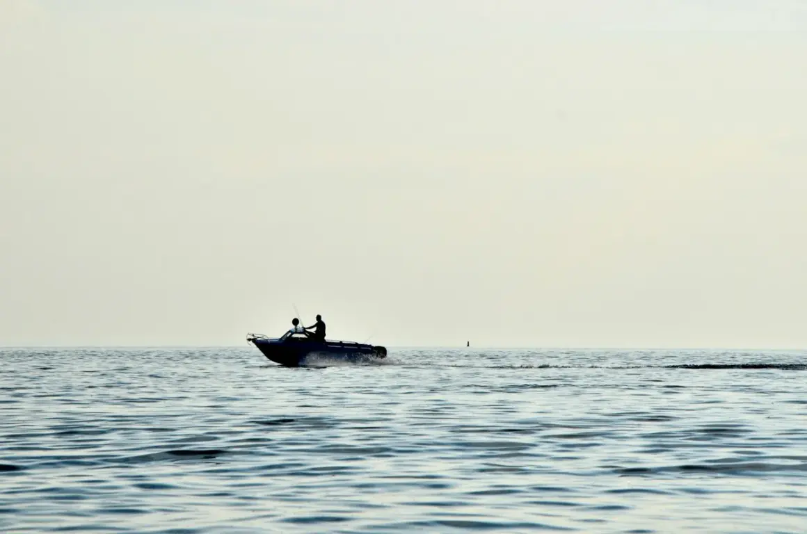 Due persone su un'imbarcazione con potenti motori marini navigano su un mare calmo, lasciando una scia d'acqua.