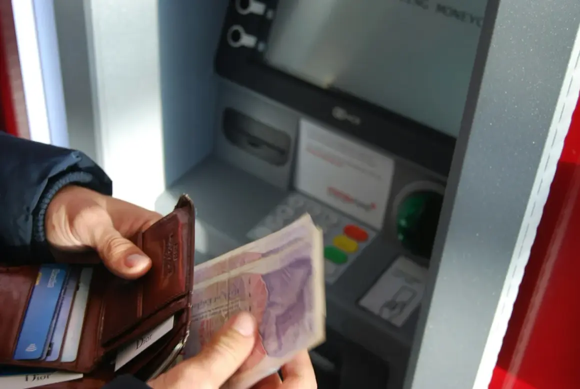 Ręka trzyma portfel z kartami i banknotami przy bankomacie. Sprawdzam saldo i dostępne środki przed wypłatą.