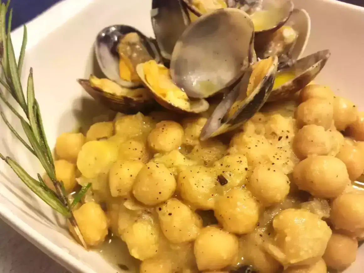 Un piatto invitante di ceci e vongole, condito con erbe aromatiche e pepe nero.