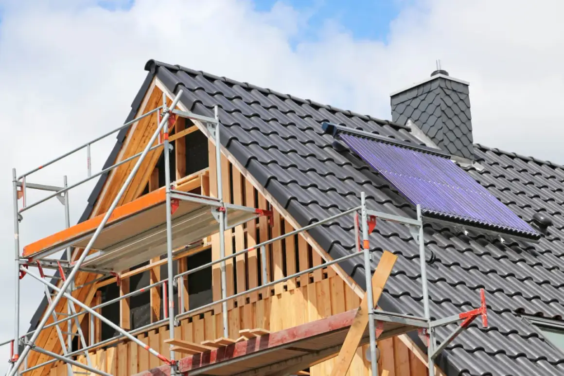 Gerüst am Dach eines Hauses, das saniert wird. Solarkollektoren sind installiert.
