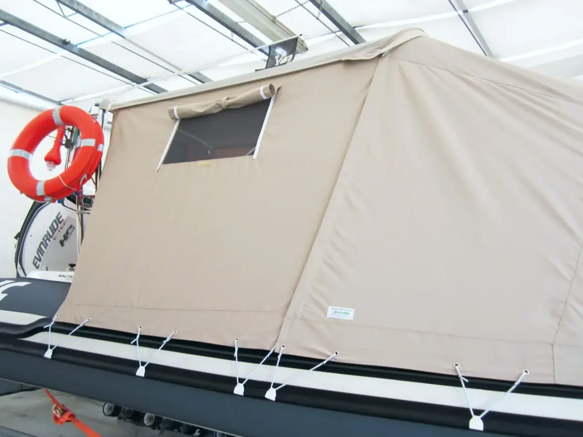 Tenda campeggio nautico su gommone, con oblò e salvagente arancione.