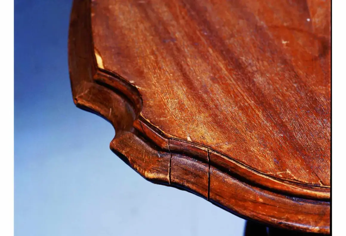 Gros plan sur le bord d'une table en bois qui se fissure, révélant les signes du temps et de l'usure.
